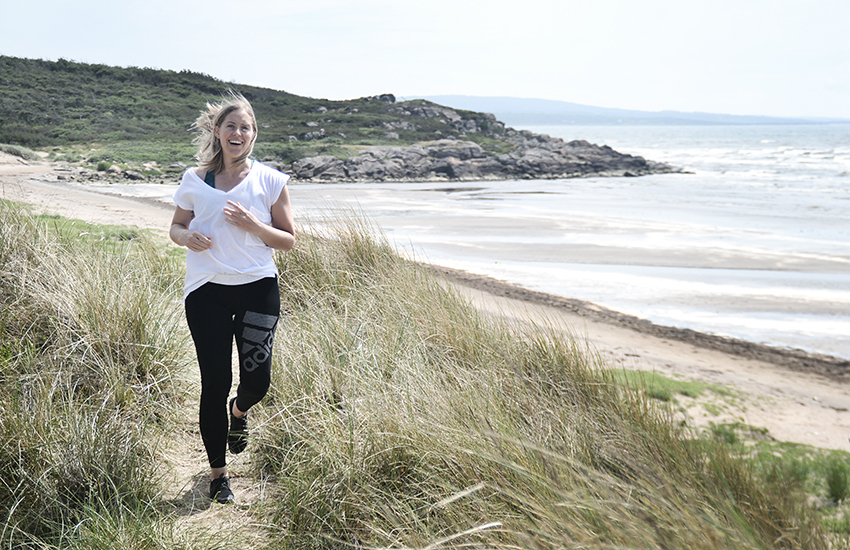 Rörelsecoach Sandra Svensson springer på stranden.