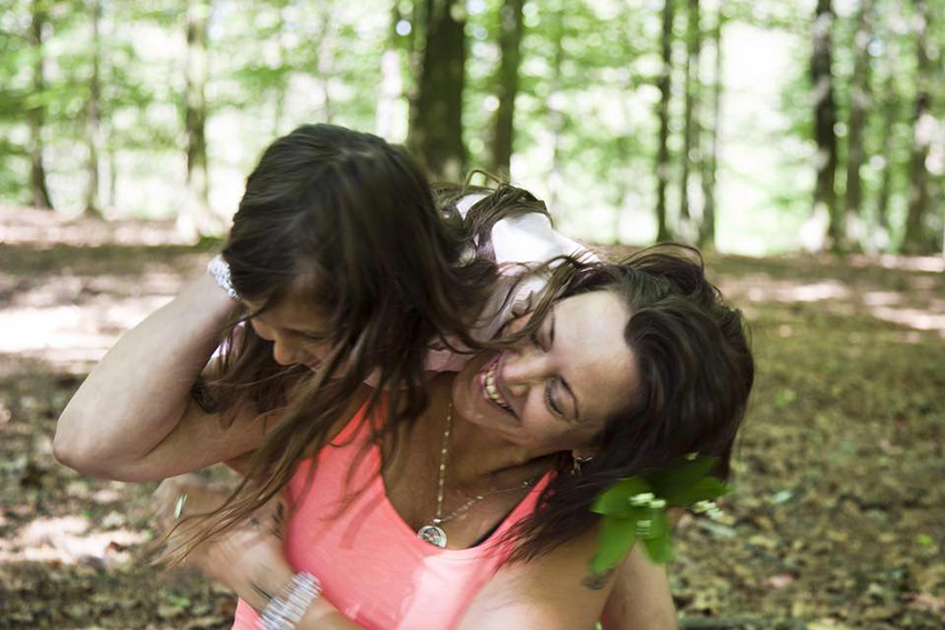Mamma och barn leker i skogen vilket visar mänsklig hållbarhet.