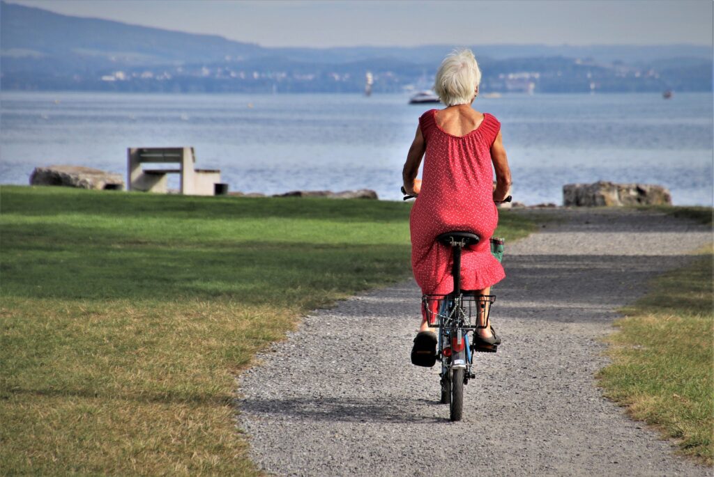 En äldre dam cyklar vid vattnet
